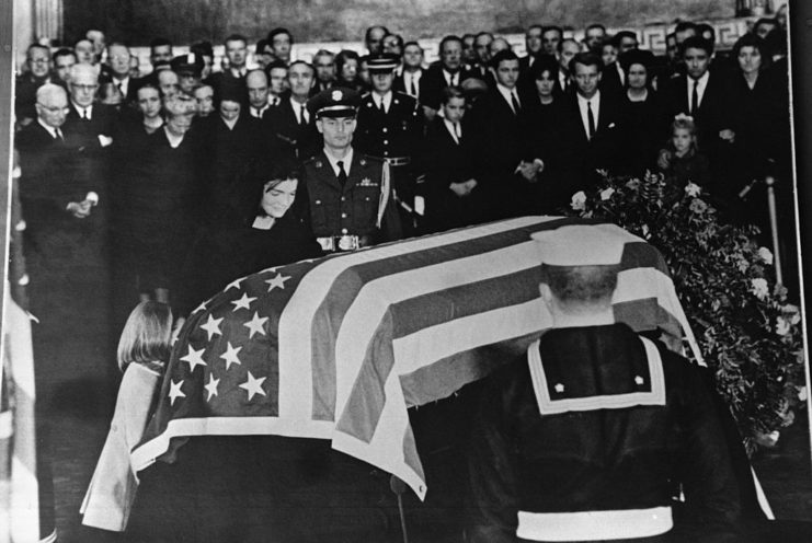 Jacqueline Kennedy standing over John F. Kennedy's flag-draped casket