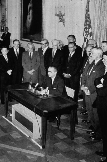 Government officials standing around Lyndon B. Johnson