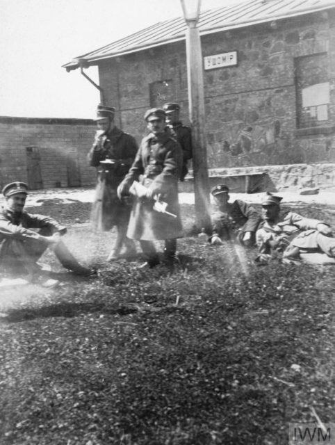 Polish soldiers resting outside, with one holding a Mauser C96 with a wooden shoulder stock