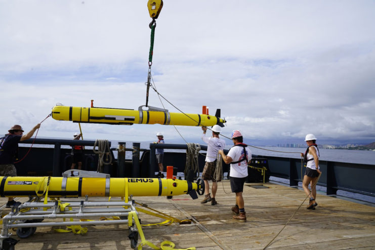 NOAA crew lifting a REMUS 600 autonomous underwater vehicle into the water