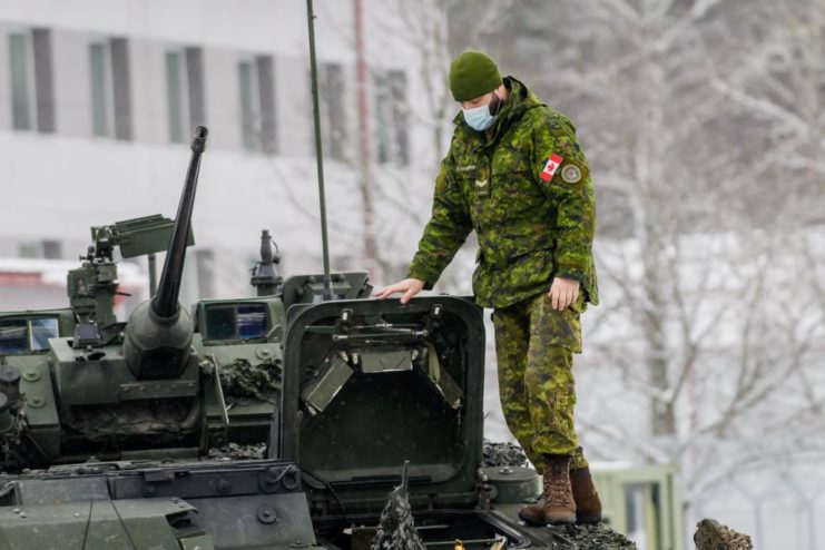 Canadian soldier standing on a military vehicle