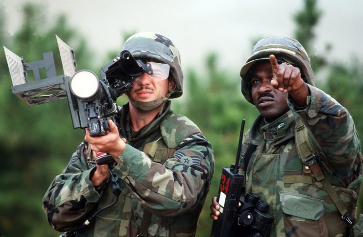 Soldier holding an FIM-92 Stinger with an IFF antenna while another points toward the target