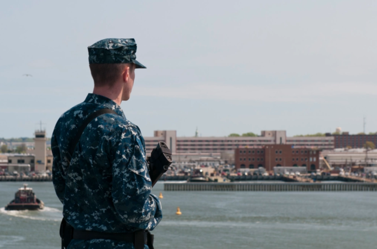 US Navy Sailor standing watch with a weapon