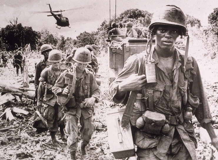American troops on patrol as a helicopter flies in the background