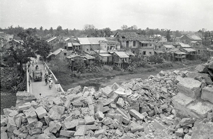 A bridge is blocked by crumbled rocks and debris in a Vietnamese village.