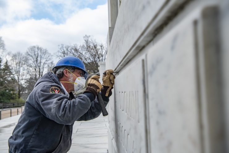 Worker hammering into the National Amphitheater cornerstone