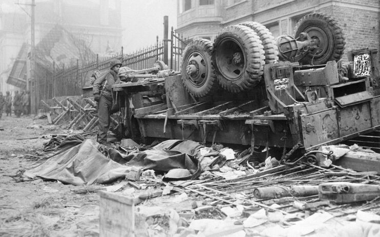 American soldier standing beside an overturned truck