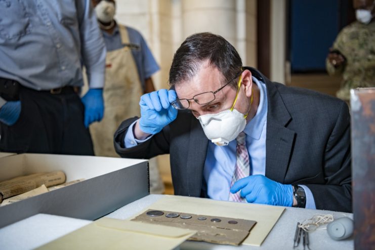 Conservator looking down at the six coins from the Memorial Amphitheater time capsule