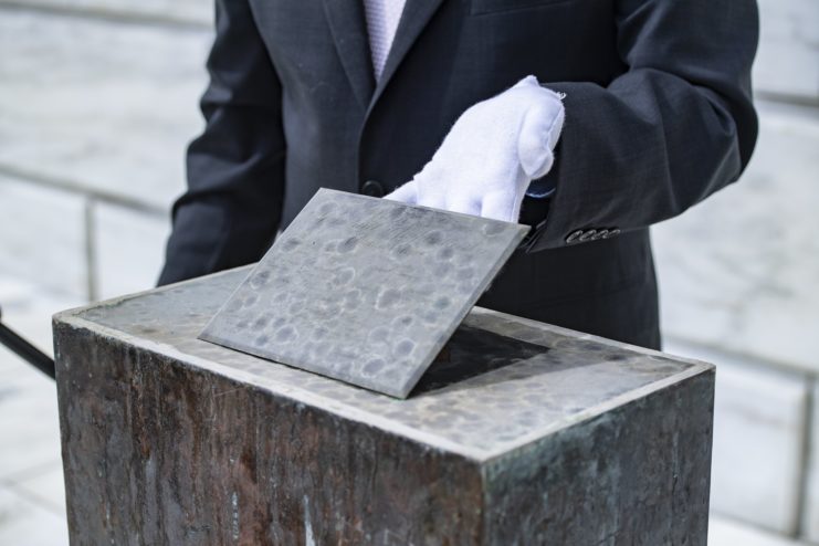 Gloved hand holding up the Memorial Amphitheater time capsule