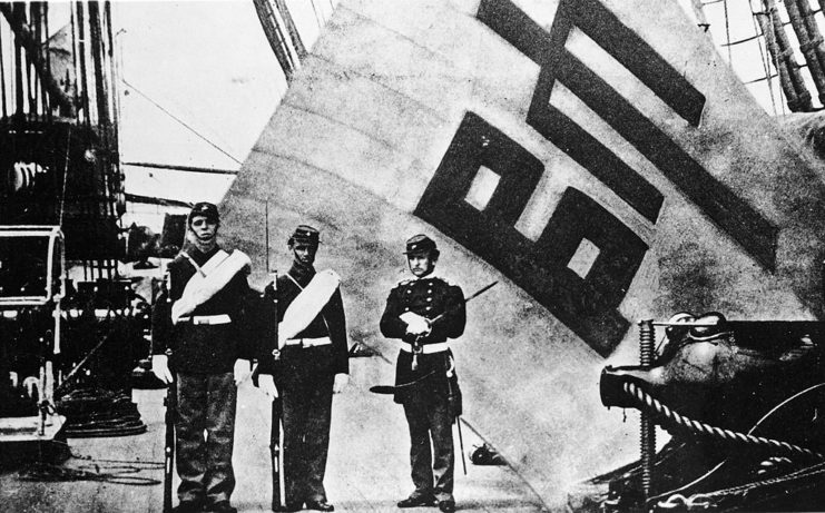 Two US Marines and one US Navy sailor standing in front of the Korean flag