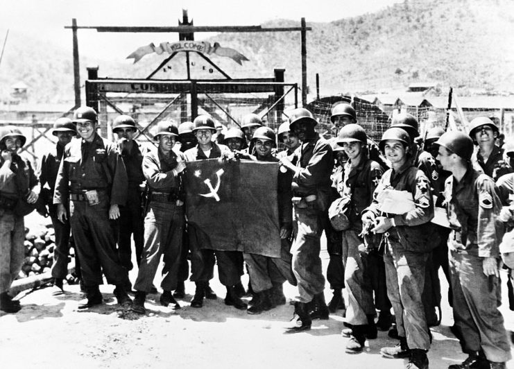 US soldiers holding a red flag with a star and sickle