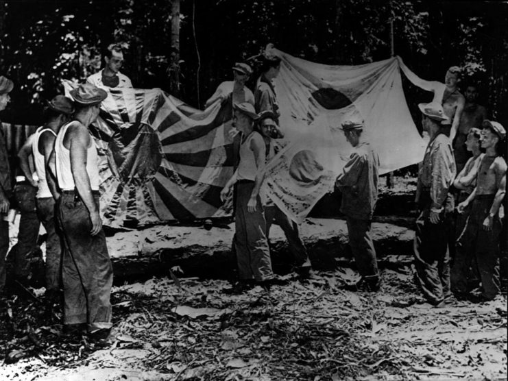 US soldiers holding up captured Japanese flags