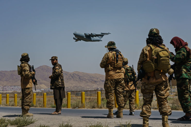 Taliban fighters watching a C-17 Globemaster take off
