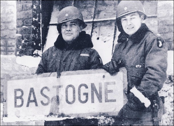 Anthony McAuliffe and Harry Kinnard II holding a sign reading "BASTOGNE"