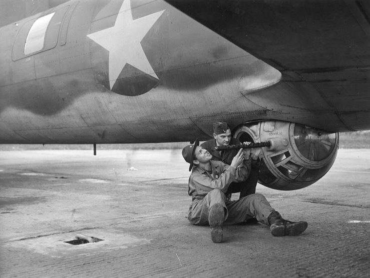 US airman showing an RAF airman the mechanisms of a ball turret