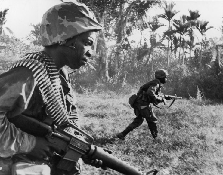 Two African-American soldiers carrying machine guns