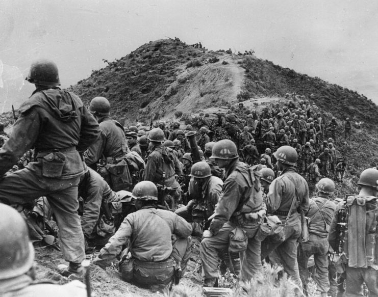 American soldiers gathered beneath a hill