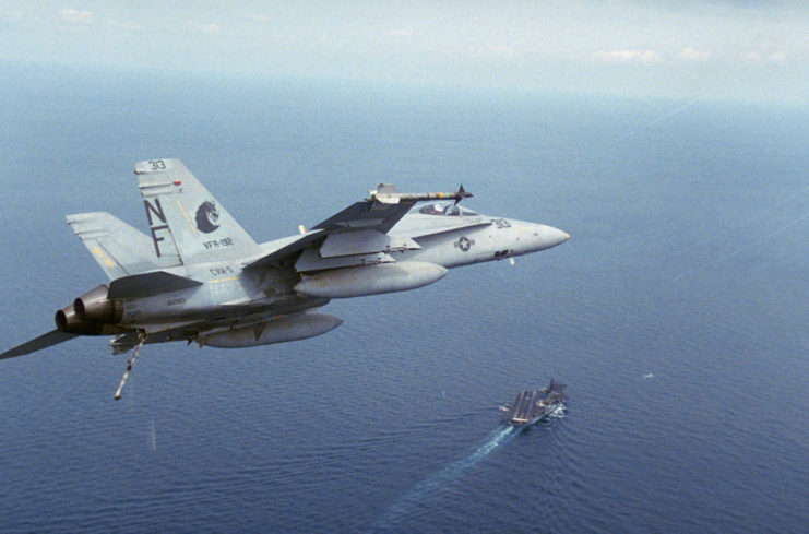 An F-18 Hornet flying over the USS Midway (CV-41)