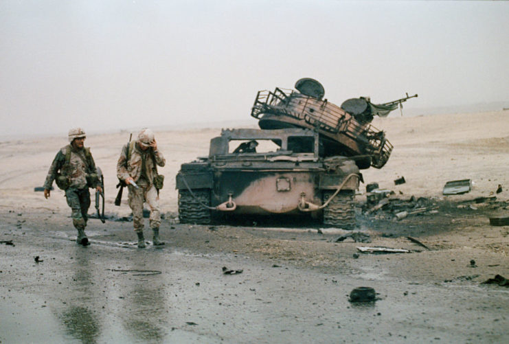 Two soldiers walking away from a damaged tank