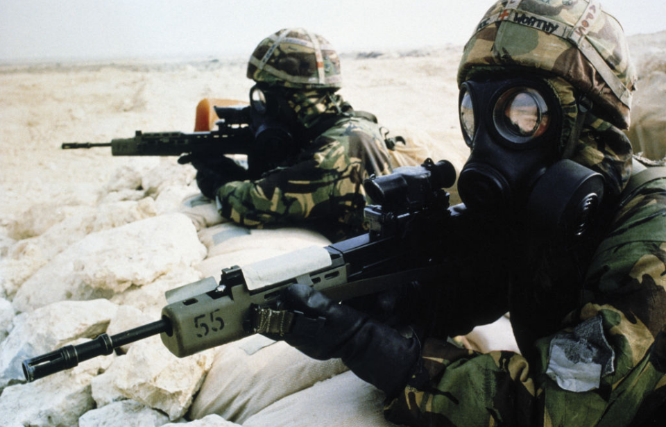 Two British soldiers dressed in chemical warfare suits and holding weapons