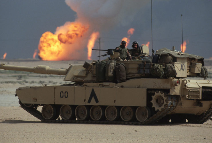 Two American soldiers standing in the turret of an M1A1 Abrams tank