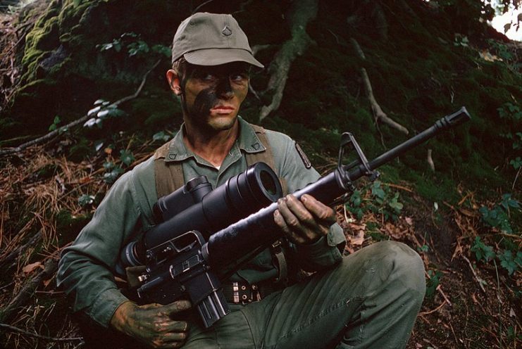 American soldier holding an M16A1 rifle equipped with a night vision scope