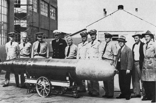 Capt. Theodore Westfall and Capt. Carl Bushnell standing with others around a Mark 14 torpedo