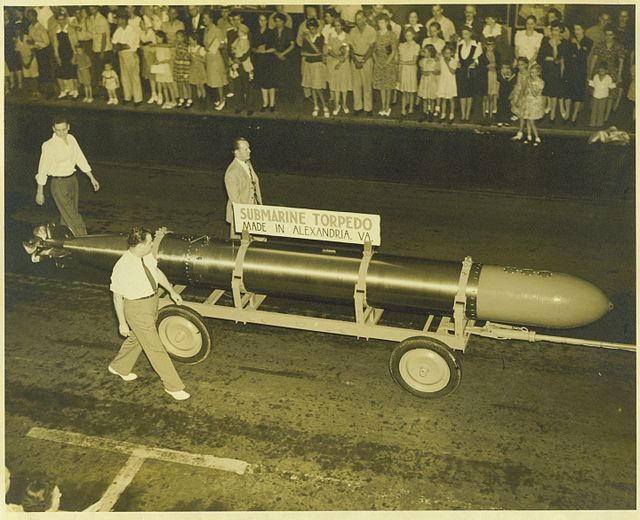 Overhead view of three men pulling along a Mark 14 torpedo