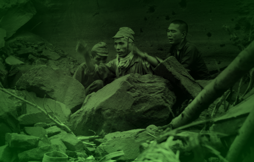 Three Japanese soldiers sitting behind a large rock