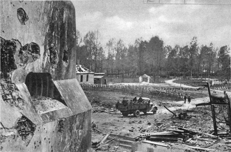 Military truck driving along a road covered in debris