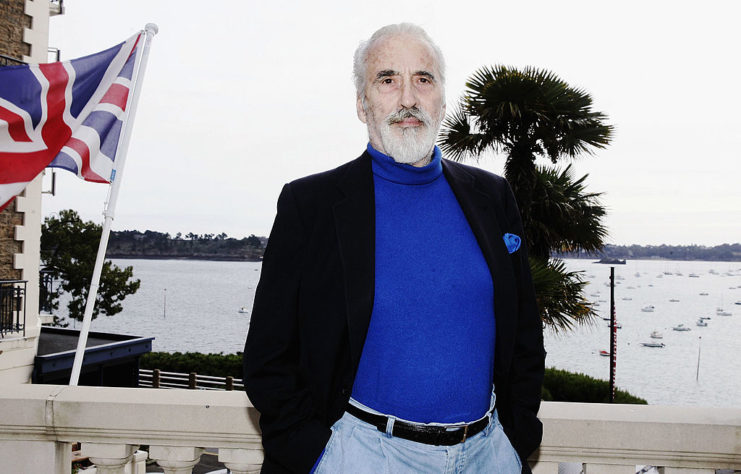 Christopher Lee standing in front of the Union Jack flag