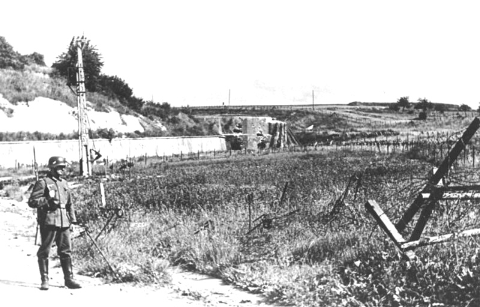 Soldier standing along the side of a dirt road