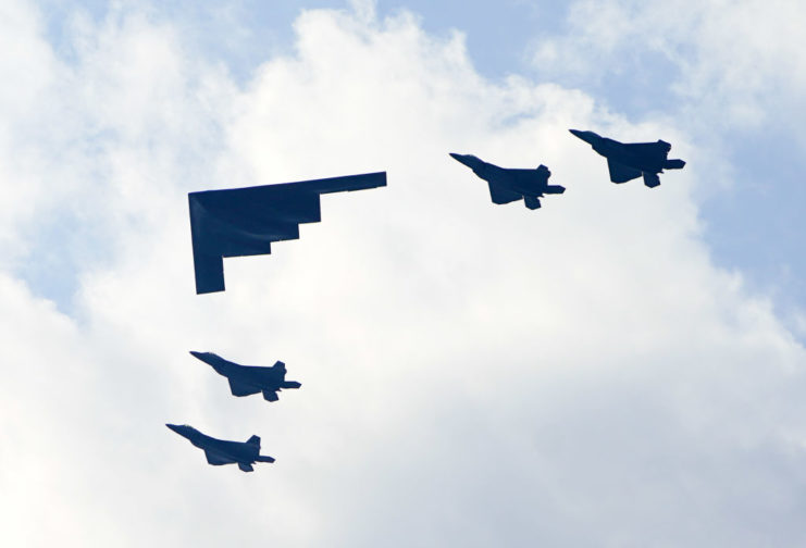 Northrop Grumman B-2 Spirit flying alongside four Lockheed Martin F-35 Lightning IIs