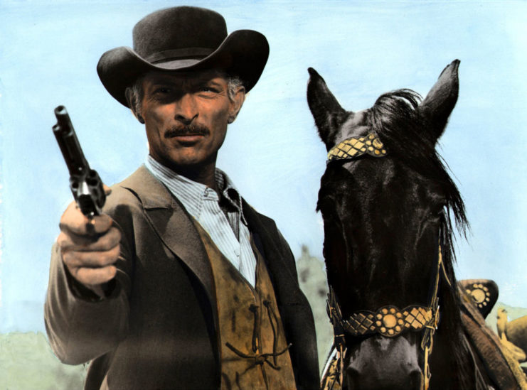 Lee Van Cleef in character, posing alongside a horse