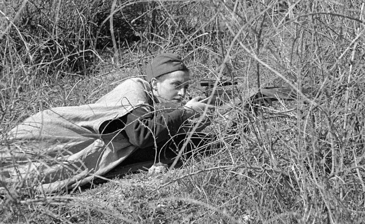 Lyudmila Pavlyuchenko lying in tall grass with her sniper rifle