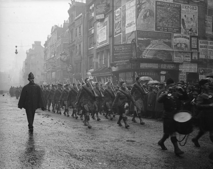 Soldiers with the Canadian Highlanders marching through a street on a rainy day