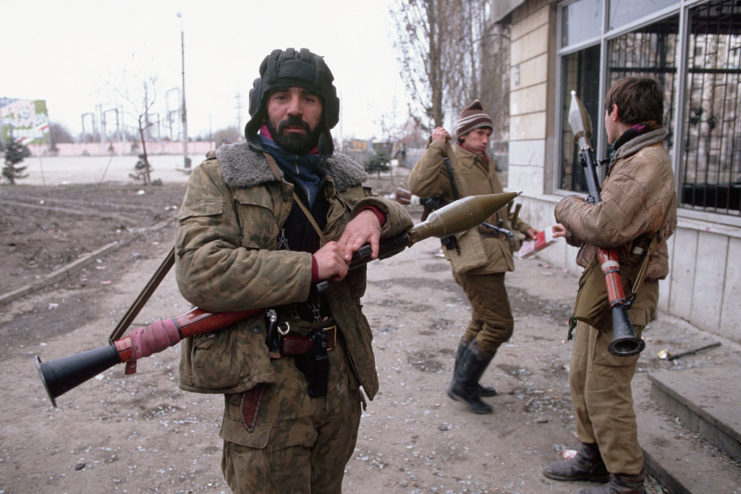 Chechen guerrillas holding bazookas while standing outside a building
