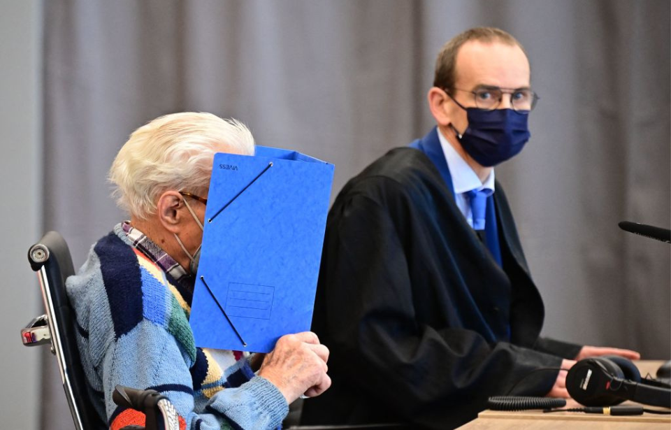 Josef S. hiding his face behind a blue folder