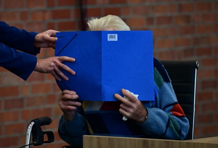 Josef S. hiding his face behind a blue folder
