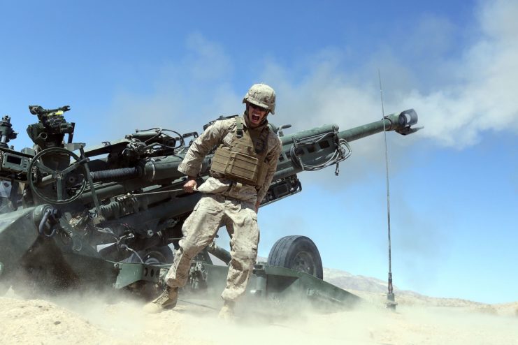 Pfc. James Miller standing in front of an M777 howitzer