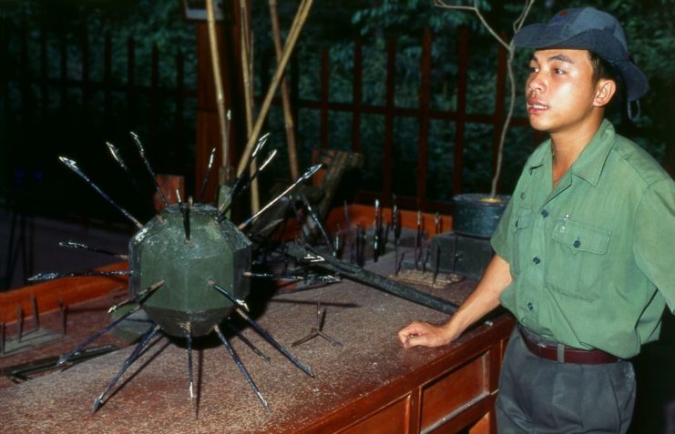 Viet Cong soldier standing next to a ball covered in spikes