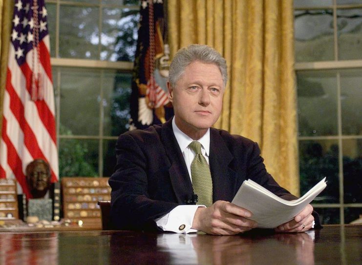 Bill Clinton seated at his desk in the Oval Office