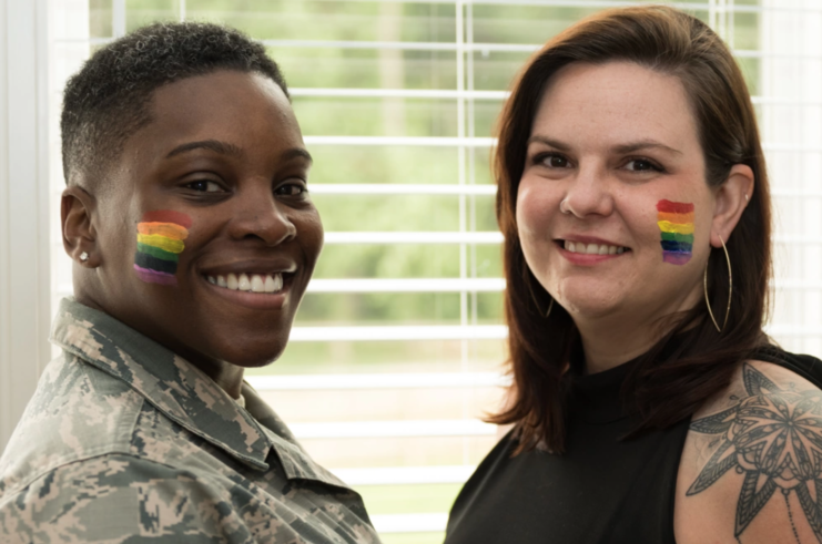 Staff Sgt.  Staci Cooper and Danie Cooper with Pride flags painted on their cheeks