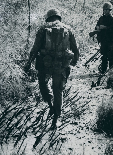 US Army soldier watching Don Burchell walk through punji sticks