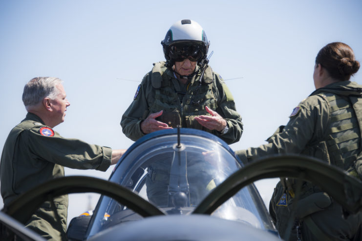 Dean Laird standing in the rear seat of a Beechcraft T-34C Turbo-Mentor, with two airmen standing on either side of him