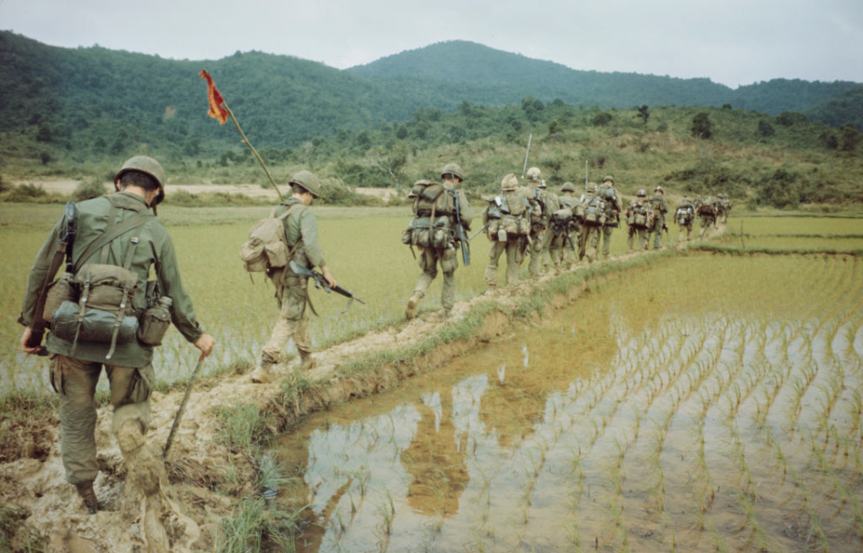 American soldiers walking along a rice field