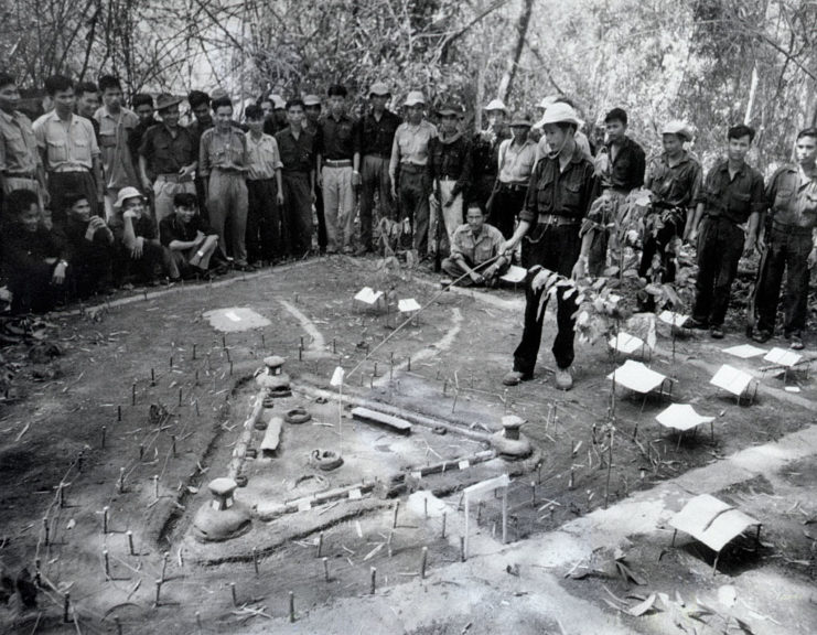 Viet Cong guerrillas standing around a model of the Bến Cầu fortress