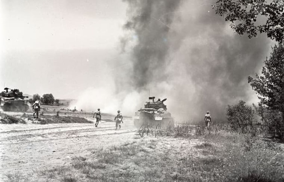 Pakistani infantrymen running behind a tank