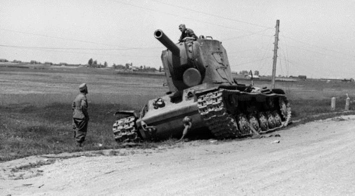 Two German soldiers inspecting a Soviet KV-2 tank along the side of a dirt road