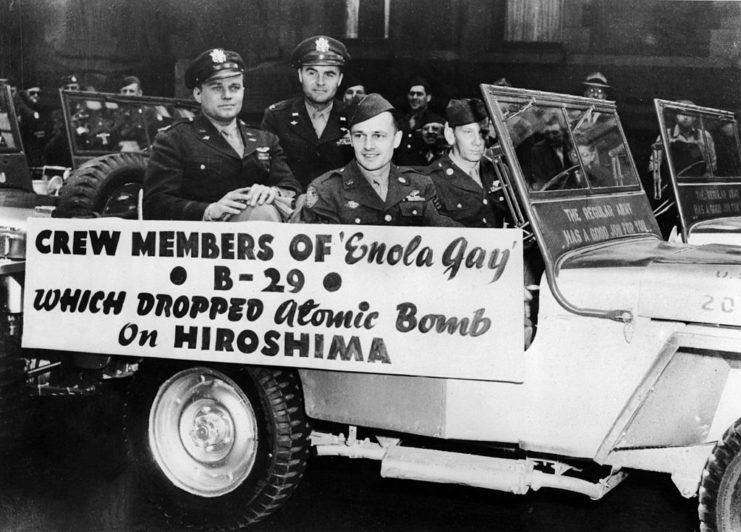 Crew of the Enola Gay riding in an open-top Jeep